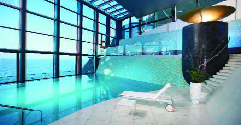 Grand Hotel Bernardin Portoroz Bagian luar foto The image showcases a luxurious indoor pool area. The pool features a clear, turquoise water and is surrounded by large glass windows, allowing natural light to flood the space and offering a scenic view. The walls have a modern design, with one side