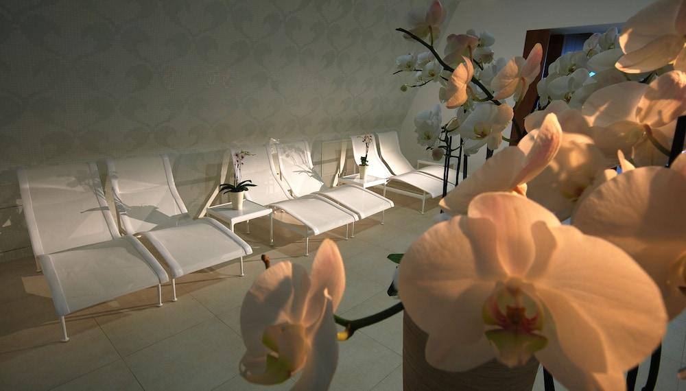 Grand Hotel Bernardin Portoroz Bagian luar foto The photo shows a serene indoor space designed for relaxation. In the foreground, there are beautiful orchid flowers, adding a touch of elegance. In the background, several white lounge chairs are arranged in a row, suggesting a spa or relaxation are