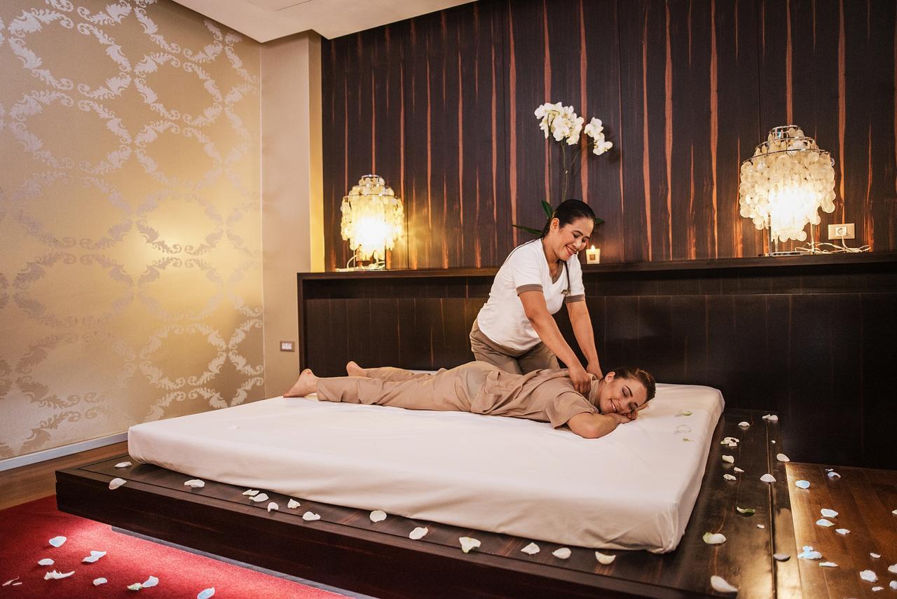 Grand Hotel Bernardin Portoroz Bagian luar foto The photo shows a relaxing spa setting where a massage therapist is performing a back massage on a client. The client is lying on a massage table, covered with a sheet and wearing a comfortable outfit. The room has a soothing ambiance, with warm ligh
